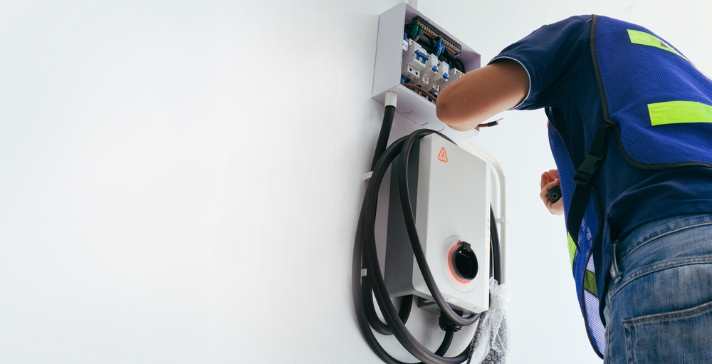 Electrician wiring a wall mounted Level 2 EV charger to the home panel
