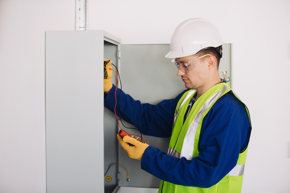 Electrician,Wearing,Safety,Helmet,And,Vest,Using,Multimeter,,Performing,Maintenance