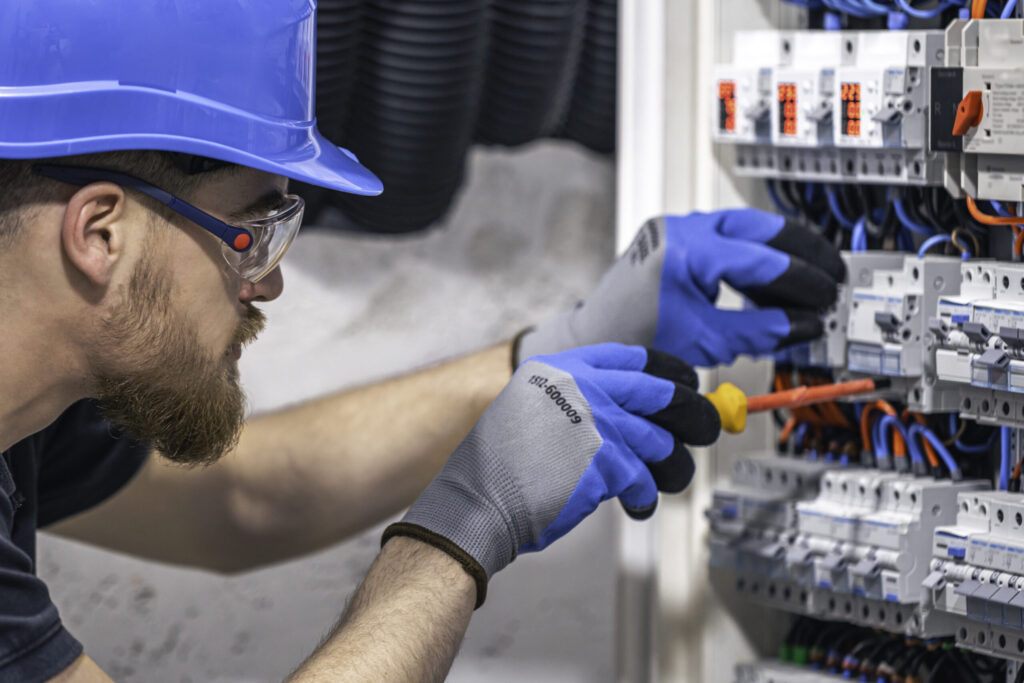 Male electrician working in a switchboard with fuses.